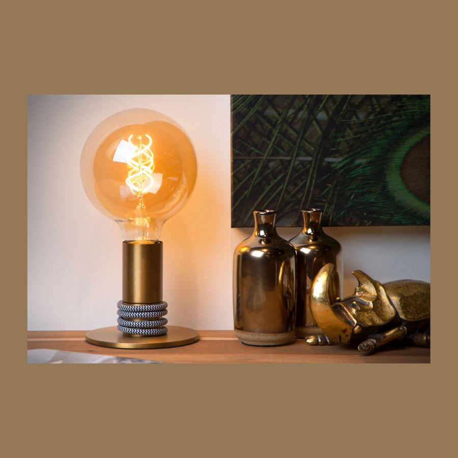 Lampe à poser dorée allumée sur une console en bois avec vases
