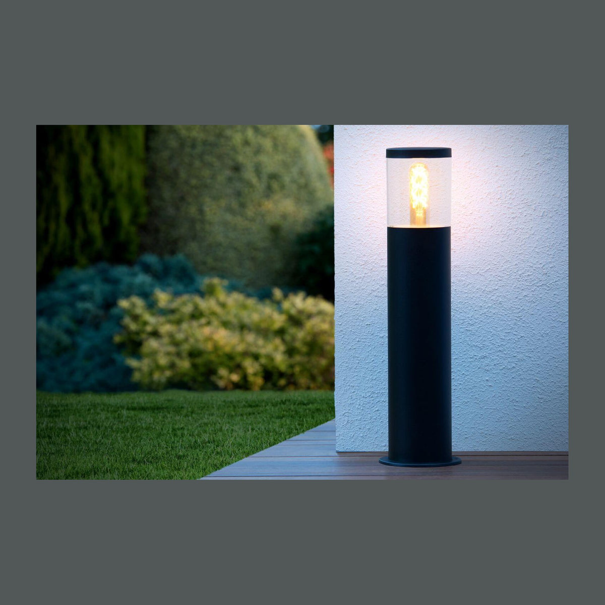 Borne noire allumée sur terrasse en bois, mur blanc et pelouse en fond