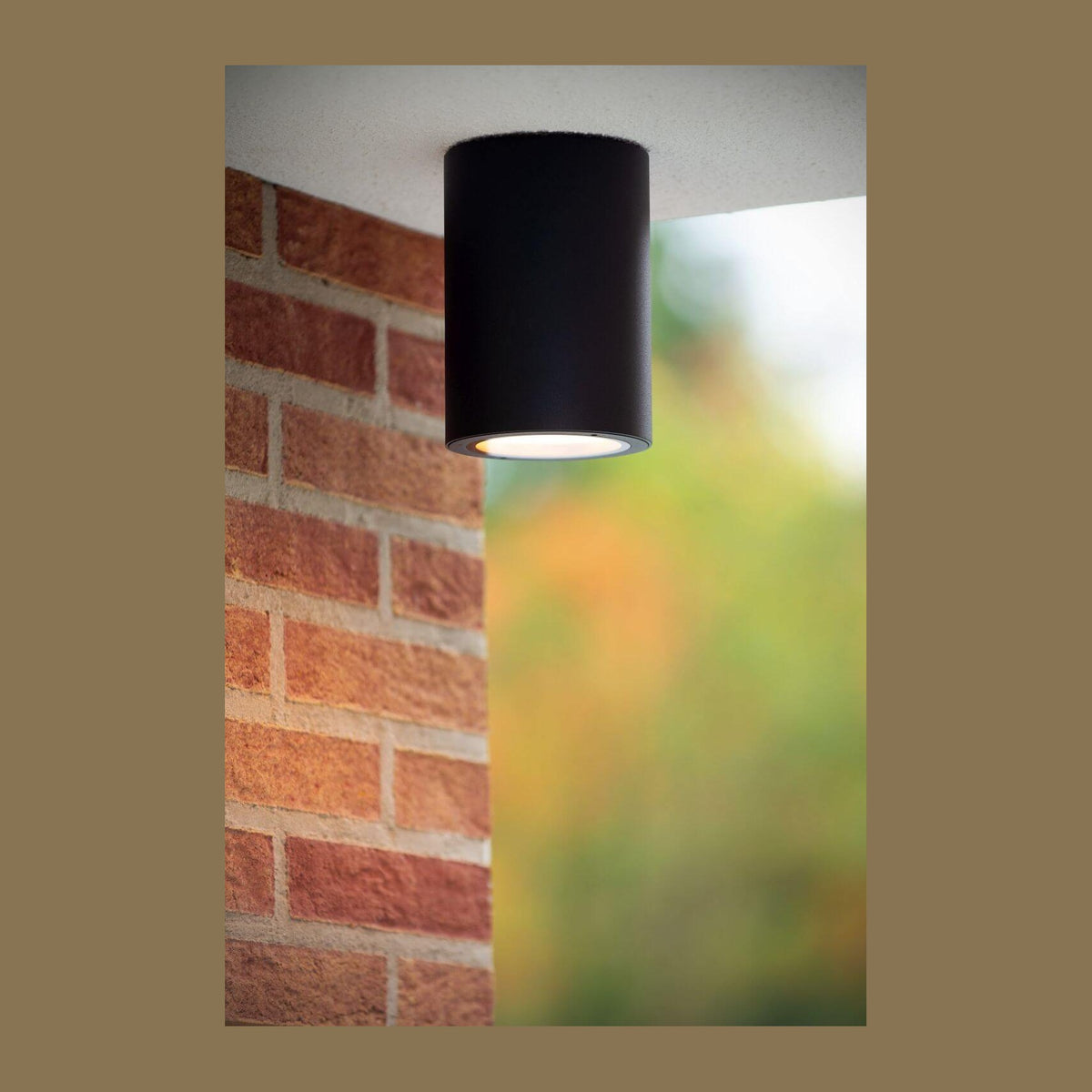 Plafonnier cylindrique noir installé en saillie sous un plafond extérieur