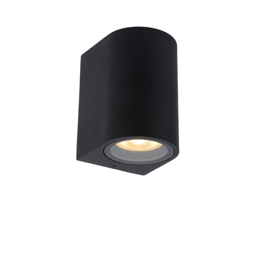 Vue trois quarts du luminaire mural noir, corps arrondi et diffuseur allumé vers le bas