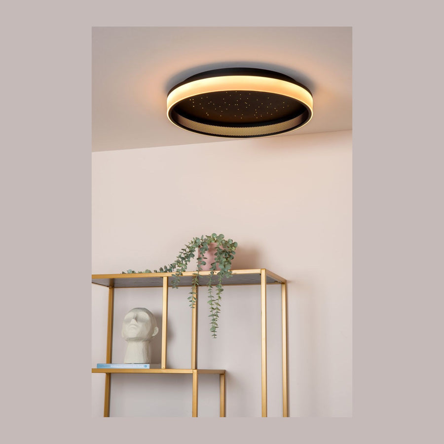 Plafonnier rond noir allumé au plafond au-dessus d'une étagère dorée