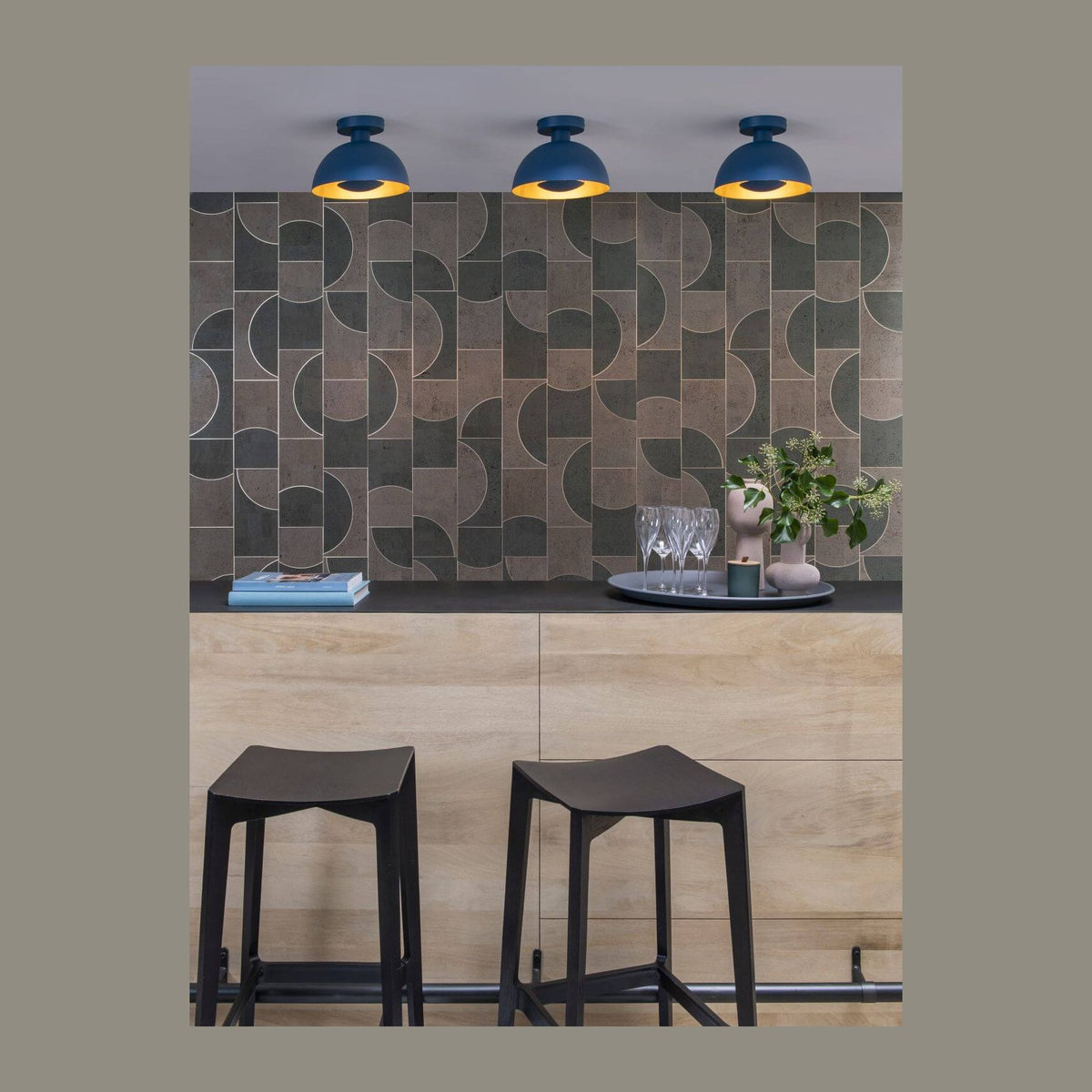 Trois plafonniers bleus au-dessus d'un comptoir de cuisine avec tabourets noirs
