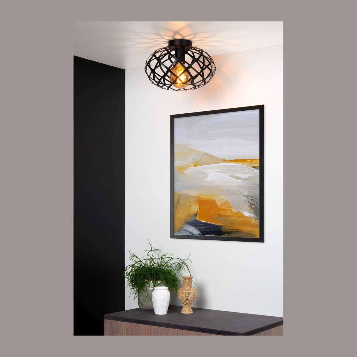 Plafonnier noir suspendu au plafond au-dessus d'une console et d'un tableau.
