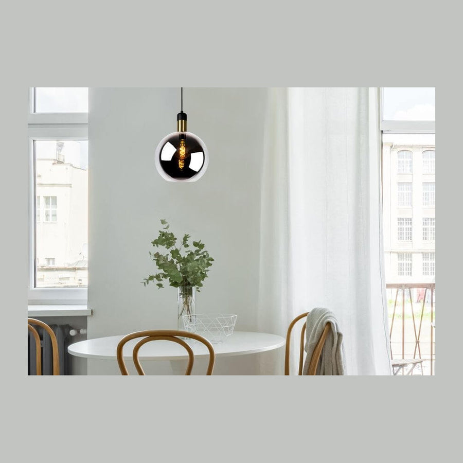 Suspension en verre fumé allumée au-dessus d'une table blanche dans un intérieur lumineux