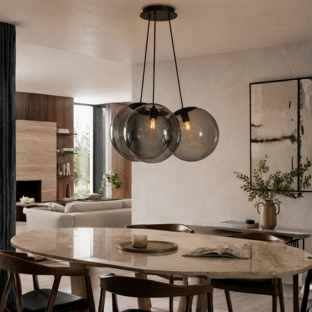 Vue en enfilade d'un salon avec suspension aux globes fumés et table en marbre.
