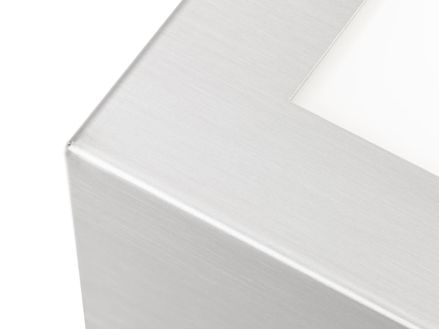 Gros plan sur l'angle et la finition brossée de l'applique en inox.