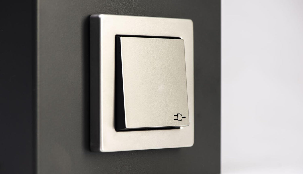 Gros plan sur l'interrupteur argenté avec icône de prise sur le luminaire.
