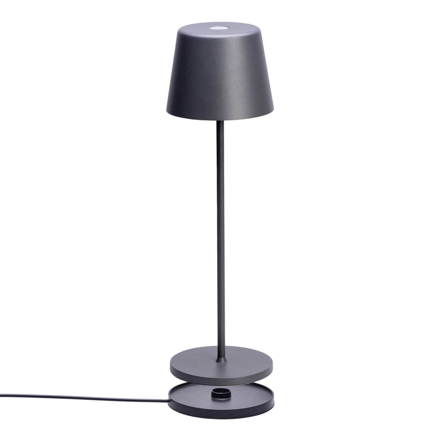 Vue de trois quarts de la lampe posée sur sa base de recharge.