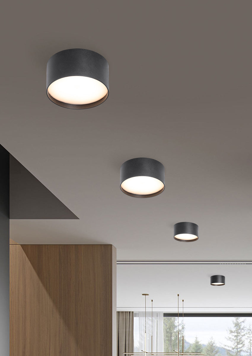 Mise en ambiance de quatre plafonniers noirs allumés sur un plafond de séjour moderne