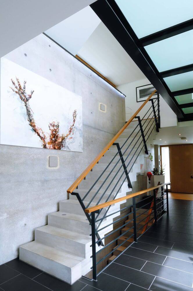 Mise en ambiance dans un escalier moderne, applique carrée discrète sur mur béton