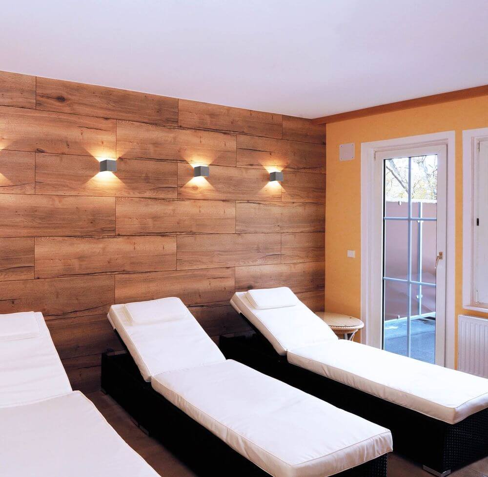 Trois appliques cubiques éclairent un mur boisé dans un espace spa.