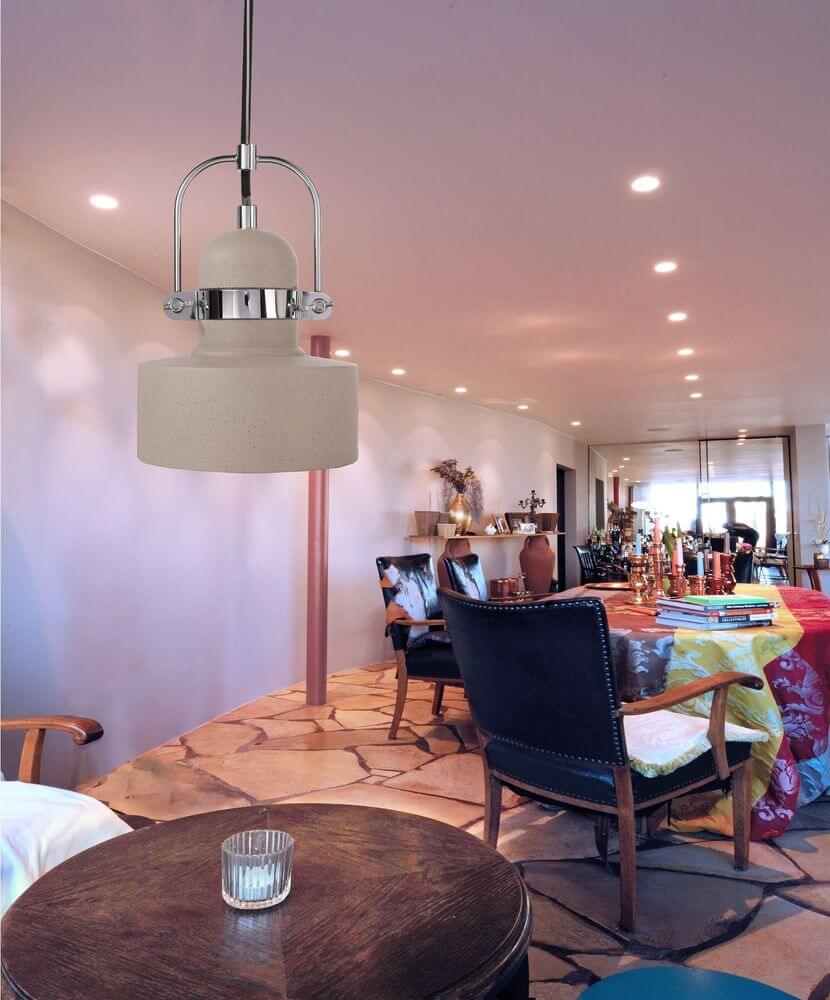 Mise en ambiance au-dessus d'une table de salle à manger, suspension béton éclairée dans un intérieur.