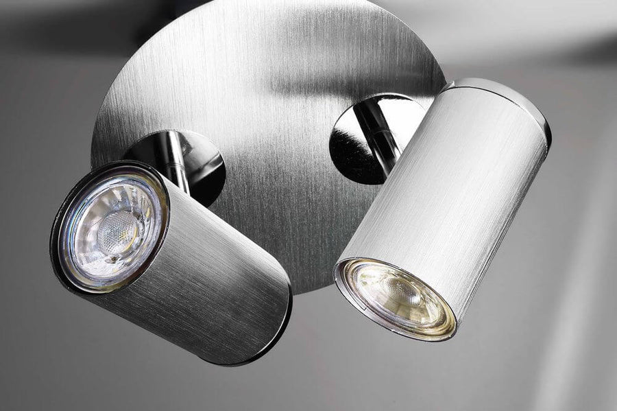 Détail rapproché des deux têtes cylindriques et de leur réflecteur en aluminium brossé.