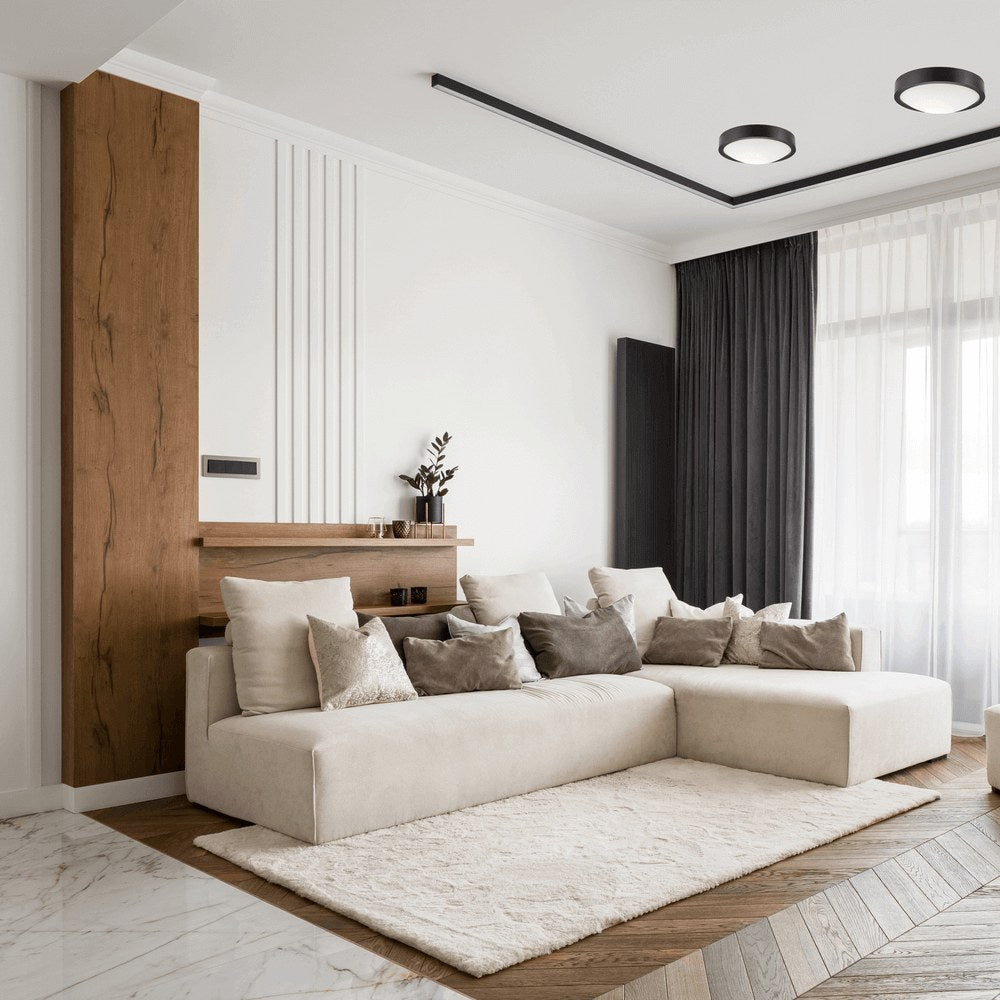 Plafonniers noirs au plafond dans un salon clair avec mur en bois et canapé beige.