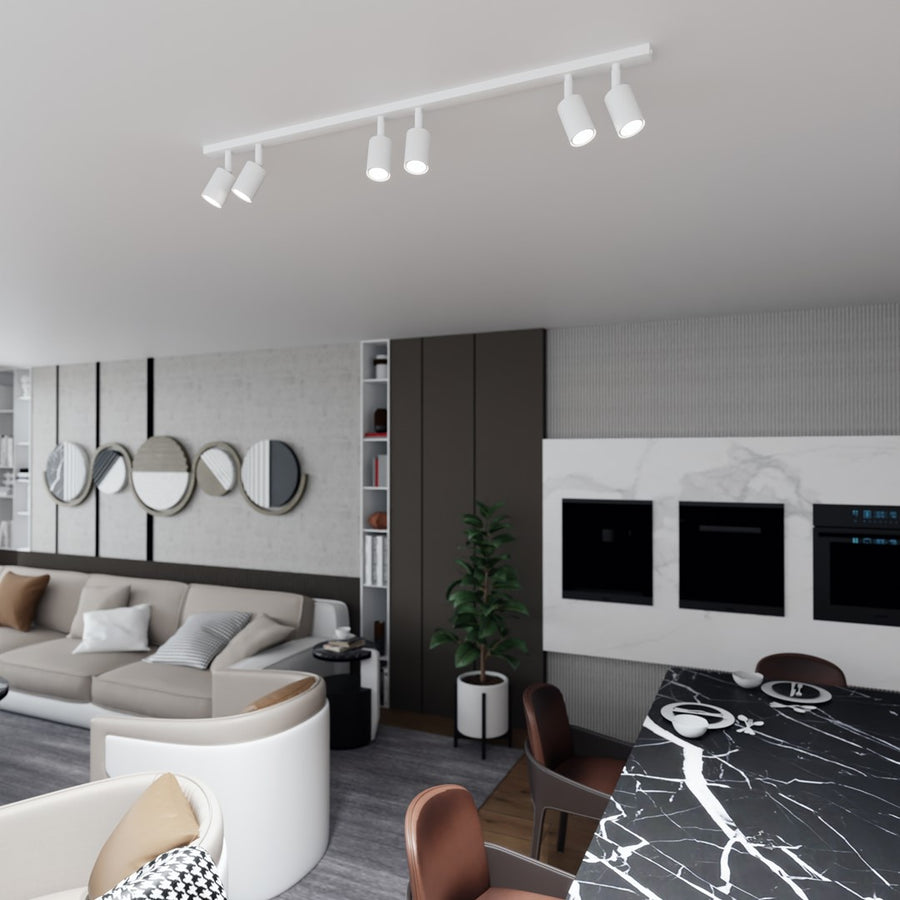 Vue large du salon avec le rail six spots blanc au plafond, au-dessus du coin repas.