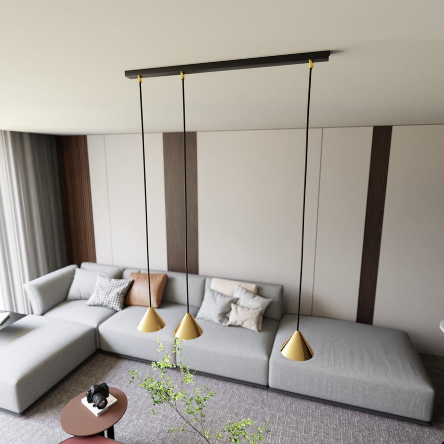 Suspension installée dans un séjour moderne, trois points dorés au-dessus d'un grand canapé gris.