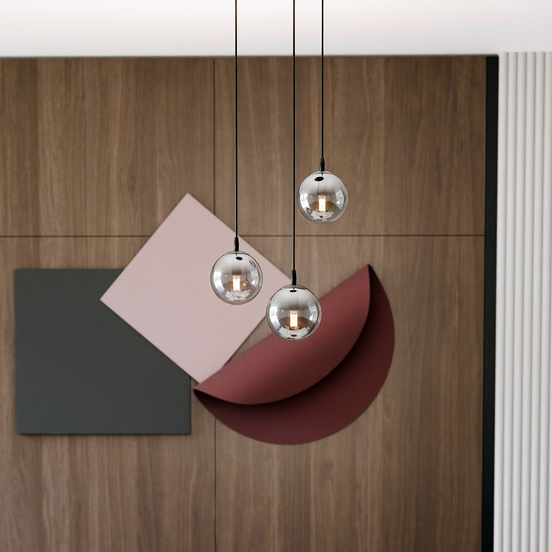 Trois globes en verre suspendus devant un panneau mural graphique en bois