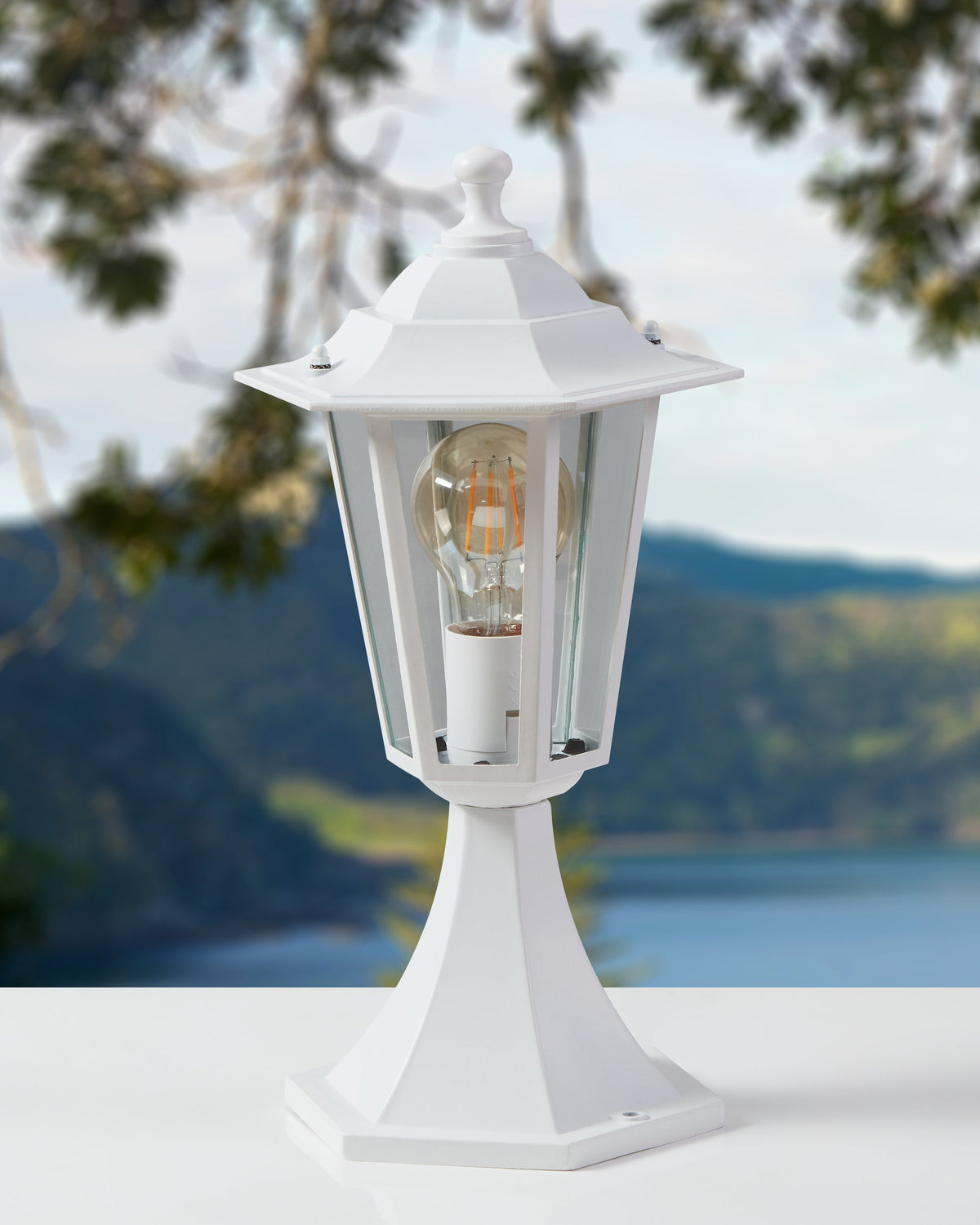 Mise en ambiance extérieure du lampadaire blanc allumé devant un paysage de lac