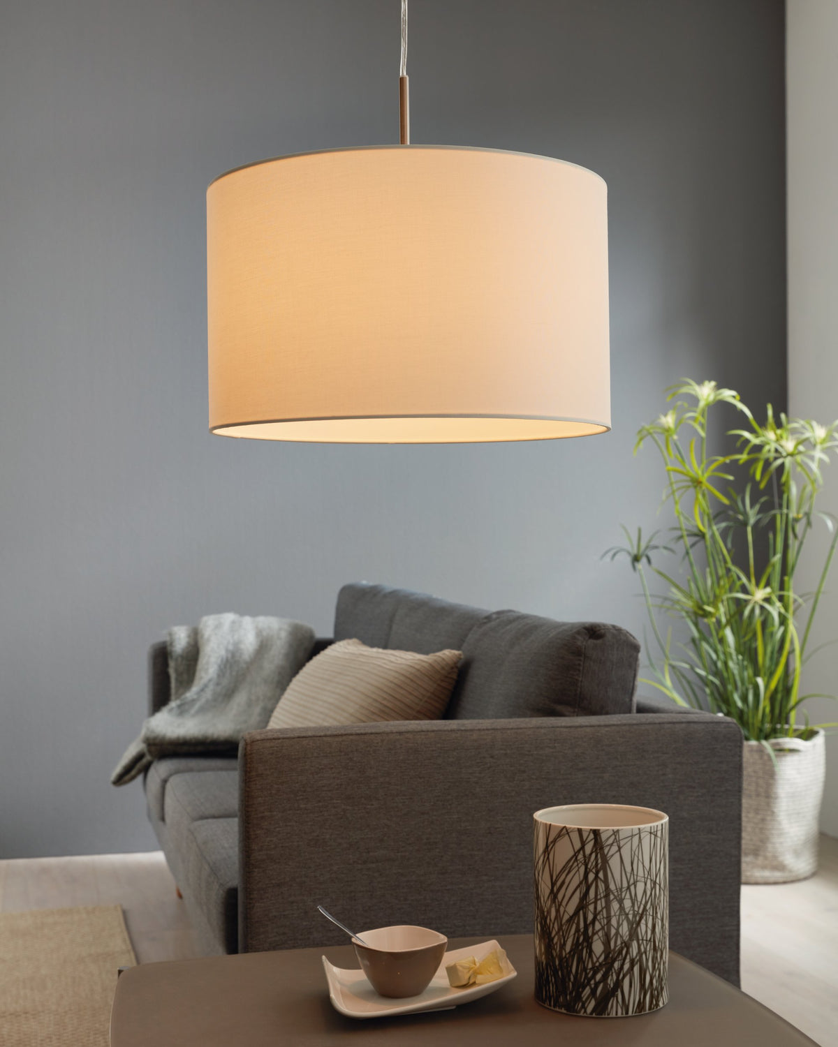Mise en ambiance dans un salon moderne, suspension allumée diffusant une lumière chaude