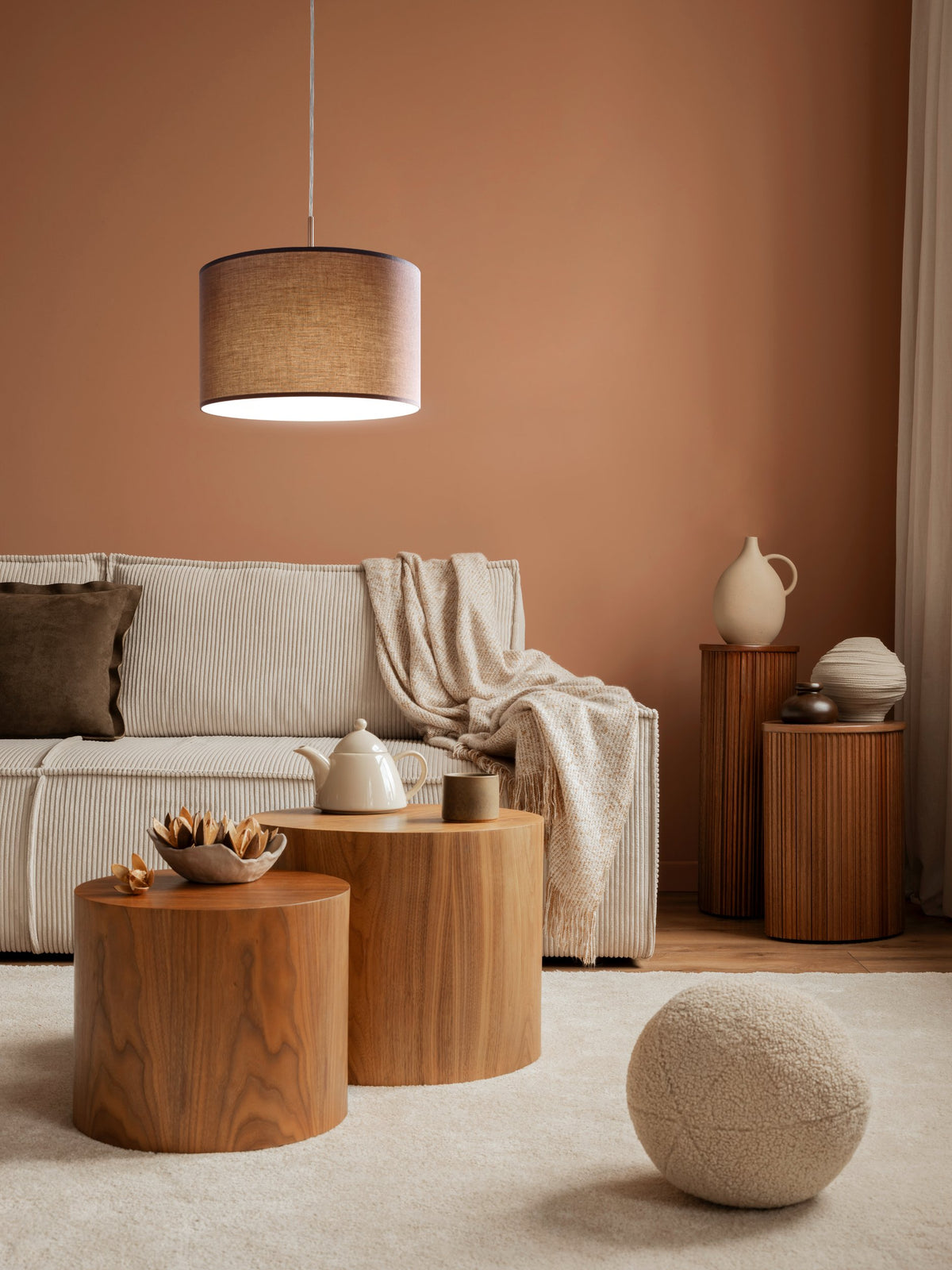 Ambiance mur terracotta, luminaire suspendu au-dessus de tables rondes en bois.