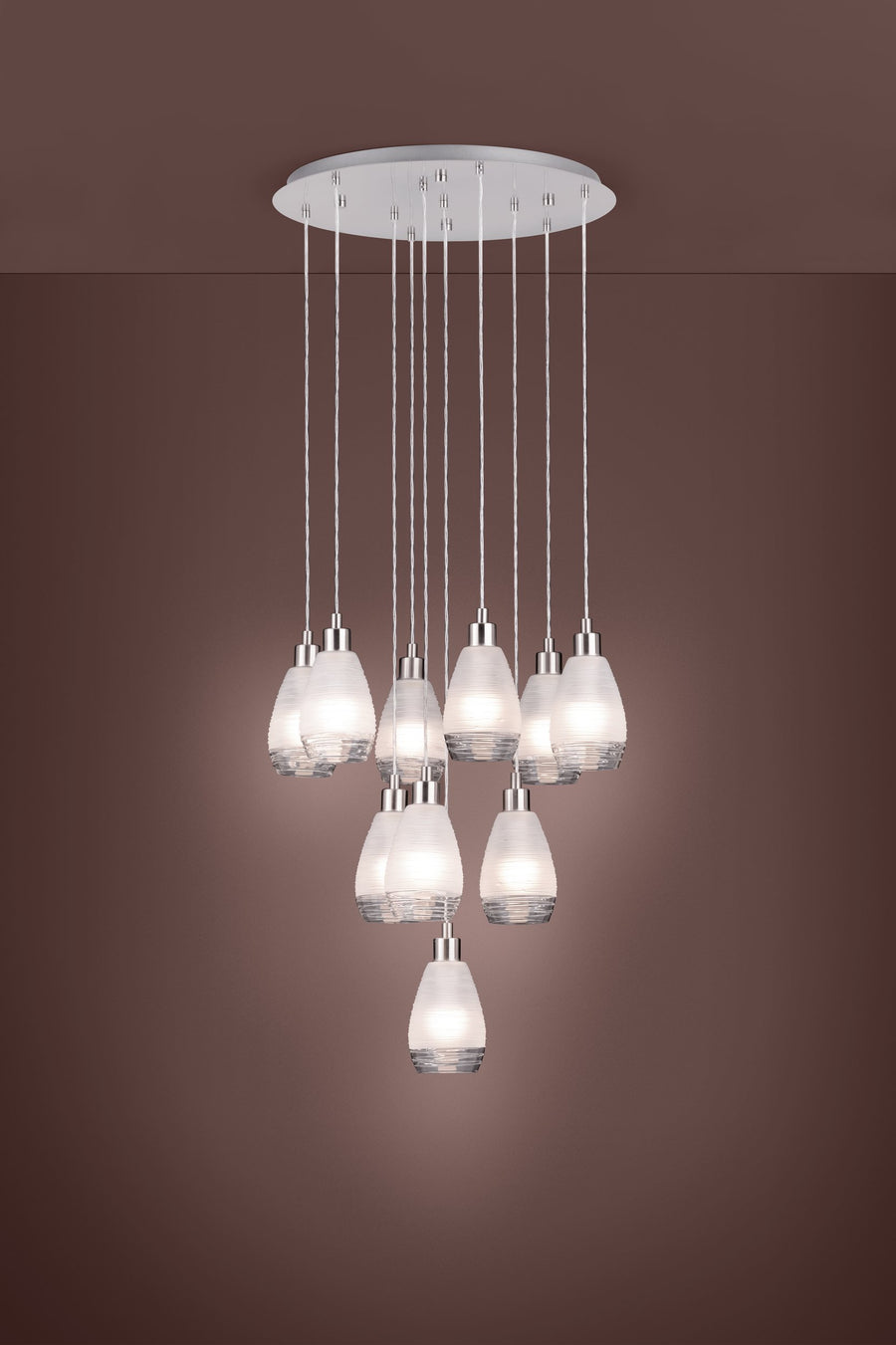Vue en situation du luminaire allumé, abat-jours diffusant une lumière chaude sur fond brun
