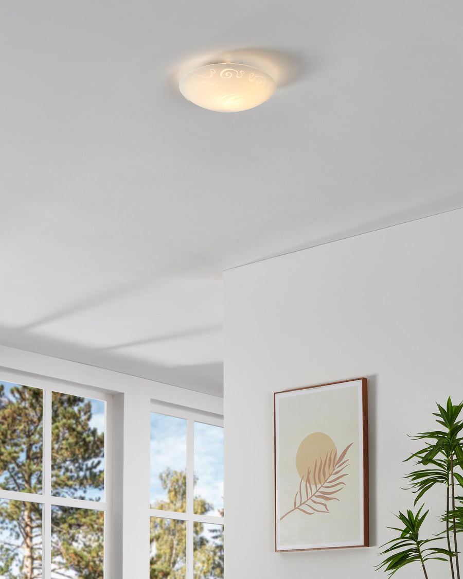Plafonnier allumé au plafond diffusant une lumière chaude dans la pièce blanche.