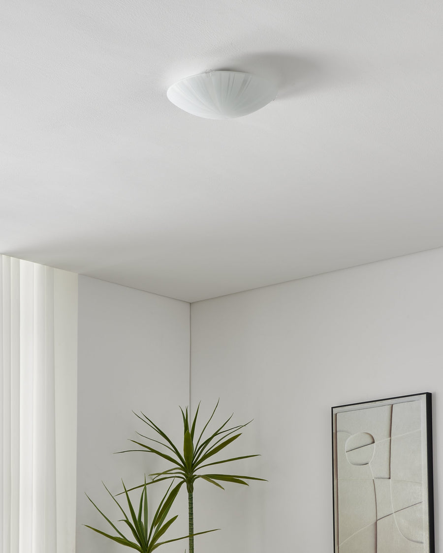 Plafonnier éteint fixé au plafond dans un intérieur blanc épuré