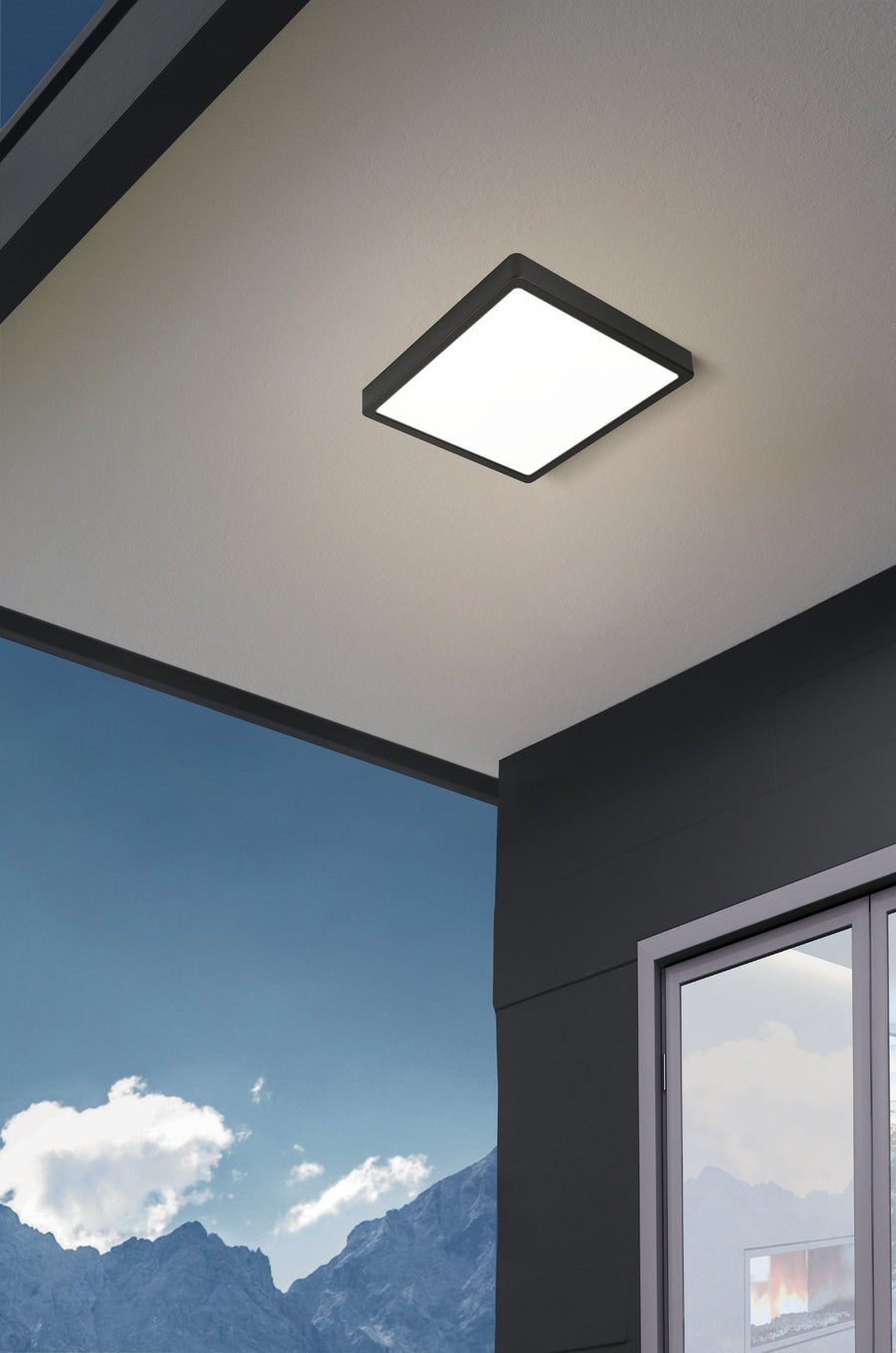 Luminaire extérieur monté au plafond sous un auvent face à la montagne.