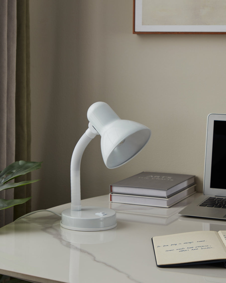 Mise en ambiance sur un bureau clair, lampe blanche allumée près d'un ordinateur portable.