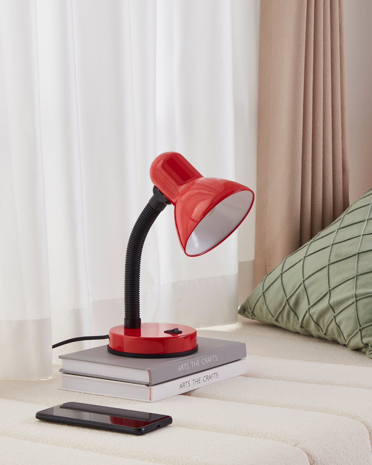 Ambiance chambre claire : lampe rouge allumée sur livres, téléphone posé devant.