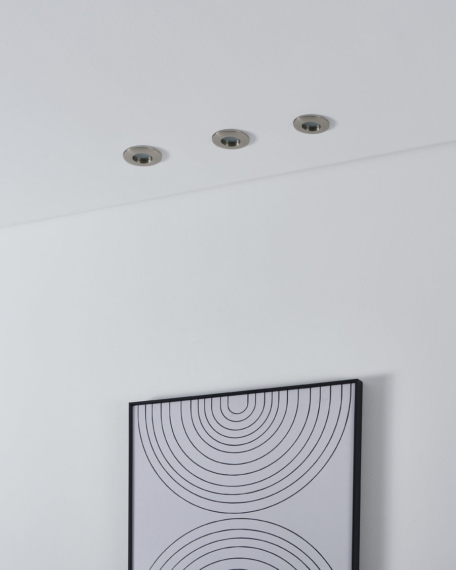 Trois spots encastrés au plafond blanc au-dessus d'un cadre graphique