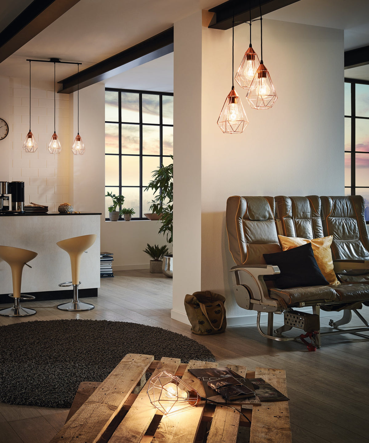 Intérieur avec suspensions cuivrées et lampe à poser allumée posée sur palette.