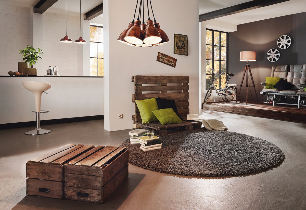 Mise en ambiance dans un intérieur industriel avec palettes bois, canapé et suspension cuivrée