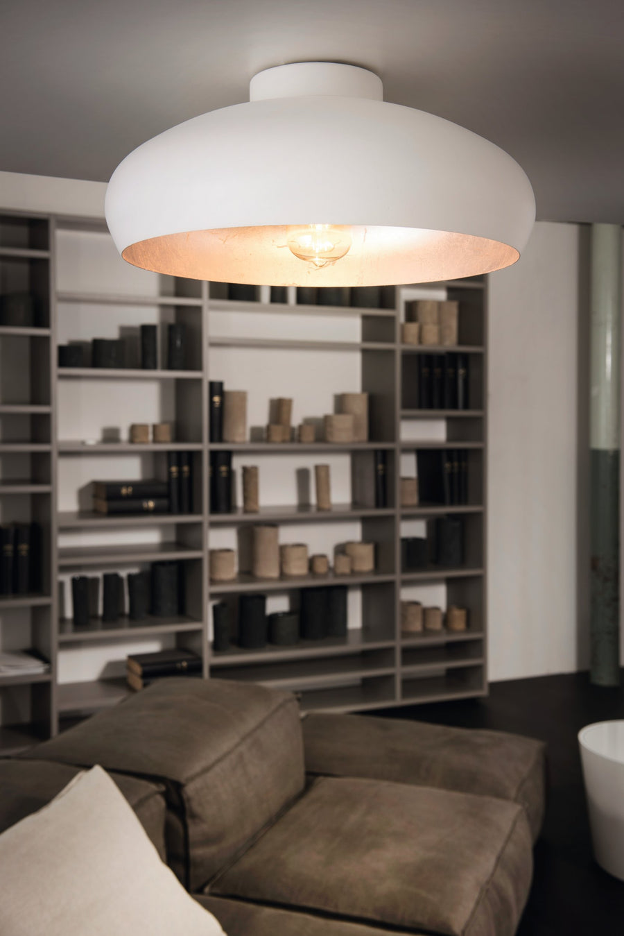 Plafonnier allumé au plafond d'un séjour sombre, lumière chaude diffusée