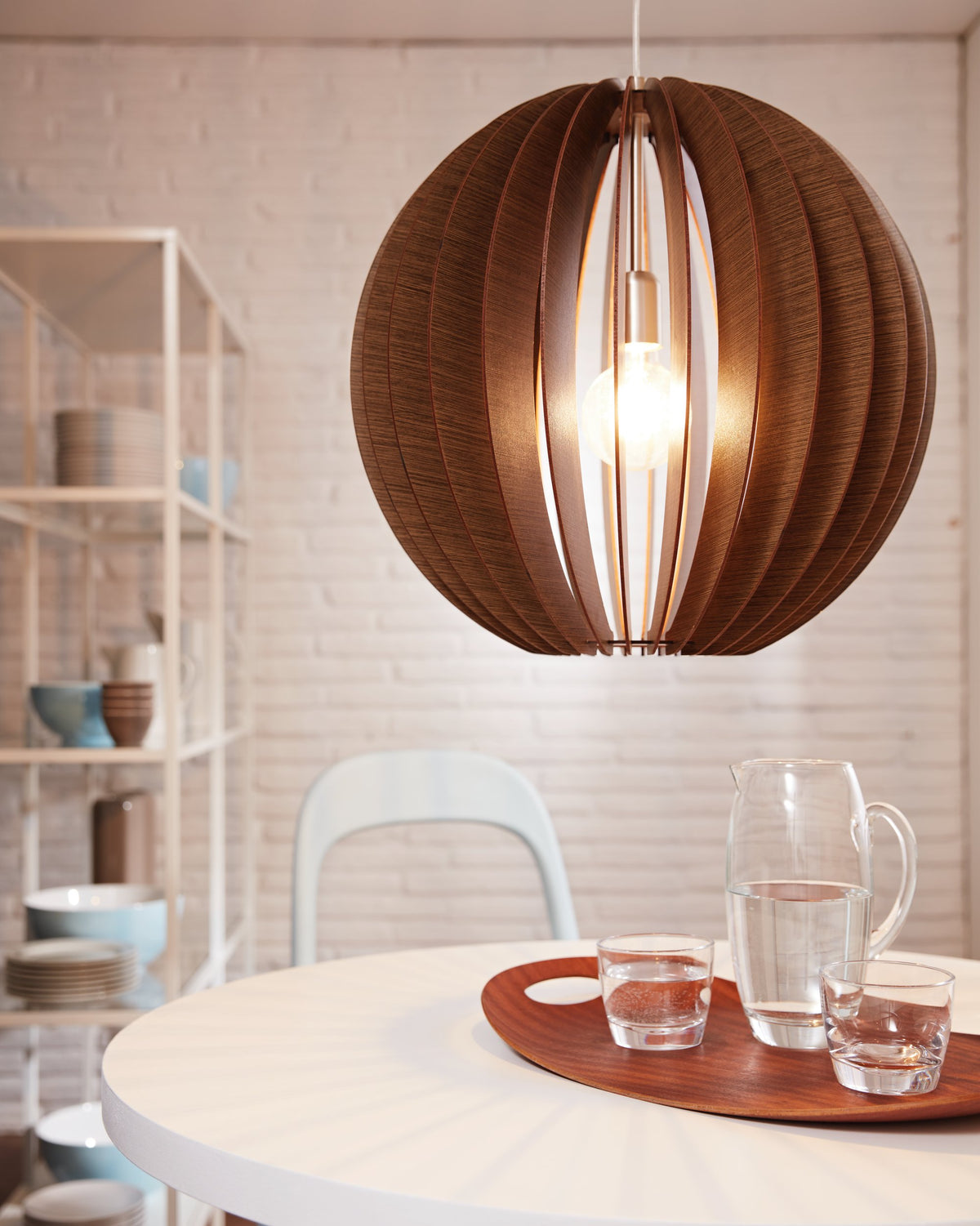 Détail de la suspension en lamelles de bois au-dessus d'une table avec carafe