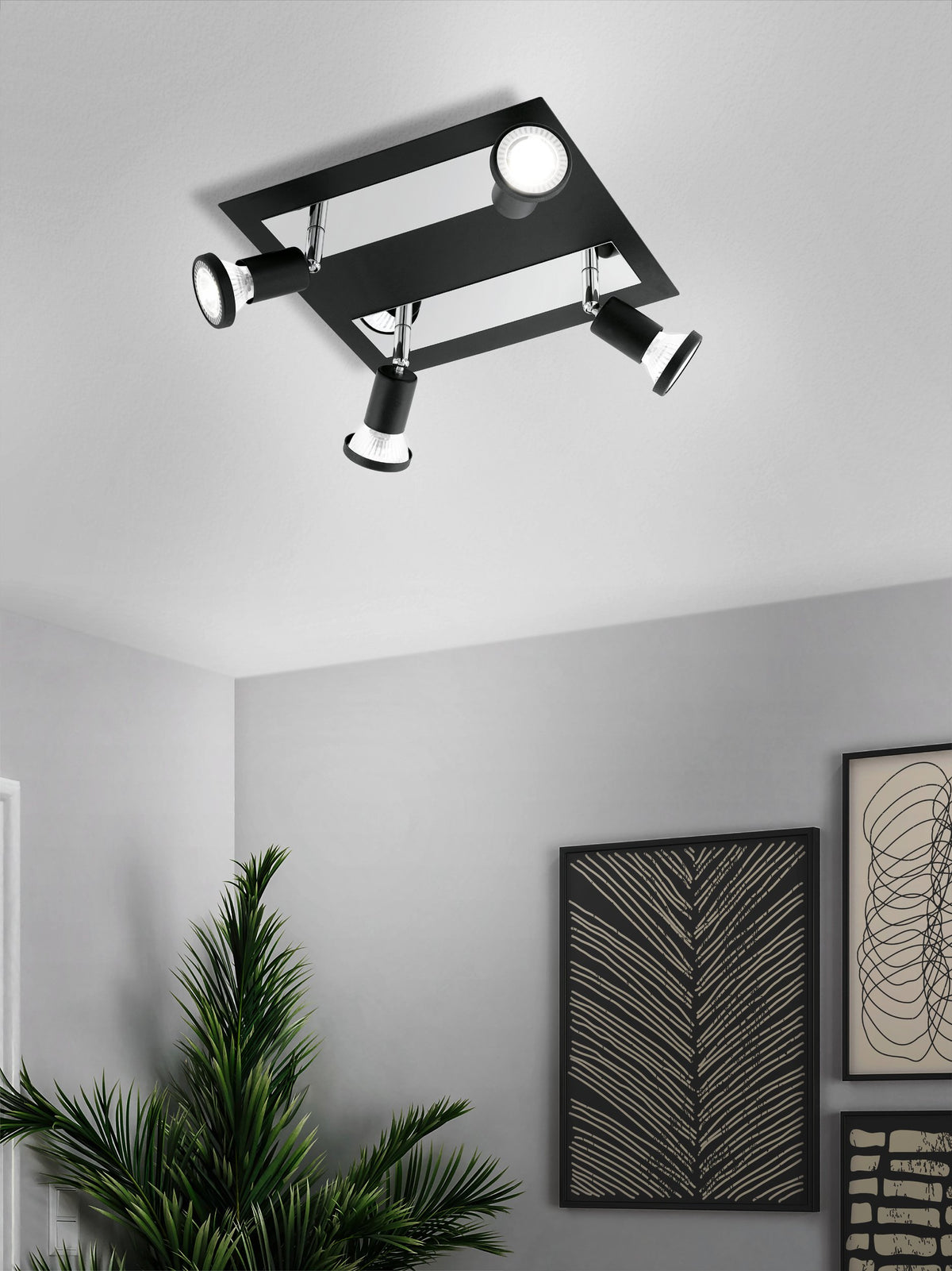 Mise en ambiance du spot plafond noir fixé au plafond, avec plante et cadres.