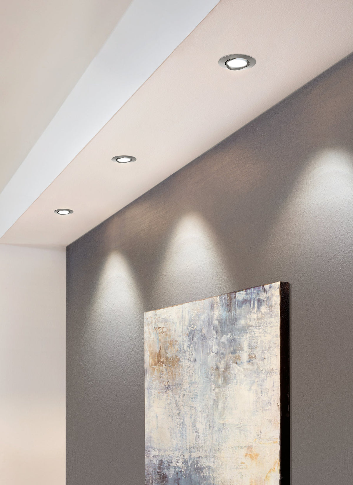 Mise en ambiance : trois spots encastrés au plafond éclairent un tableau mural