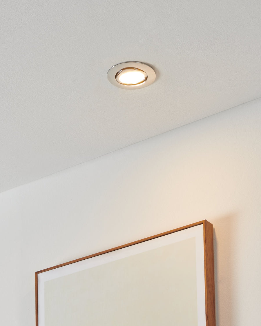 Spot encastré allumé au plafond, halo lumineux doré sur fond blanc