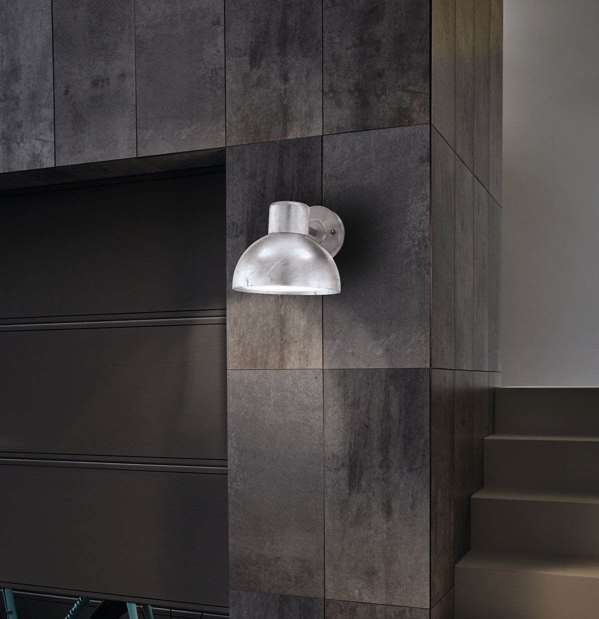 Mise en ambiance sur un mur de carrelage anthracite près d'un escalier intérieur.