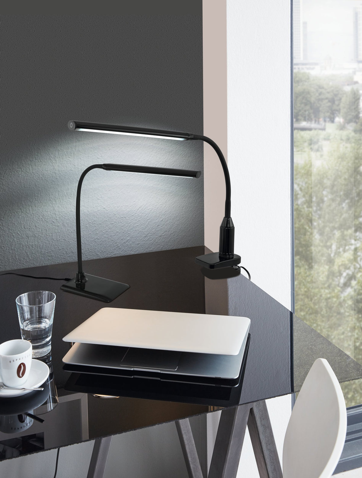 Deux lampes noires éclairent un bureau sombre avec ordinateur portable et tasse espresso
