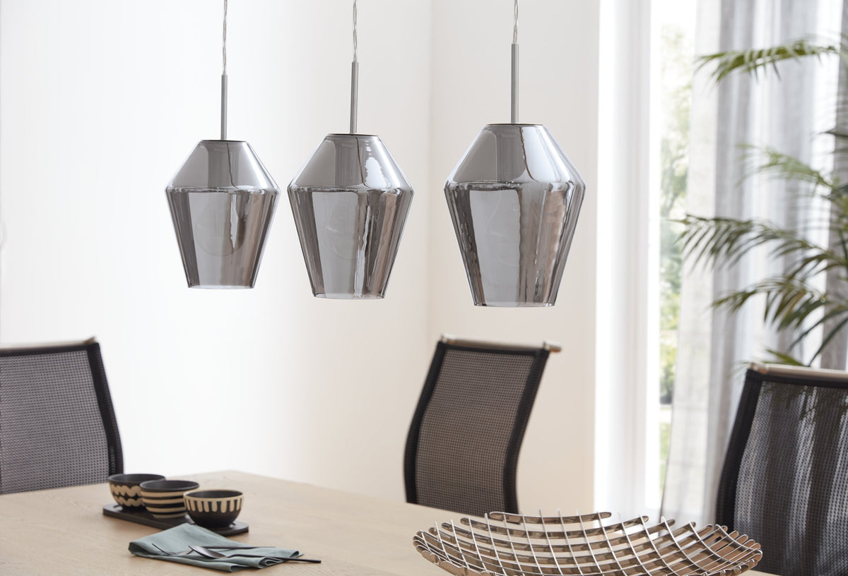 Mise en ambiance au-dessus d'une table à manger, trois suspensions en verre fumé et chaises noires