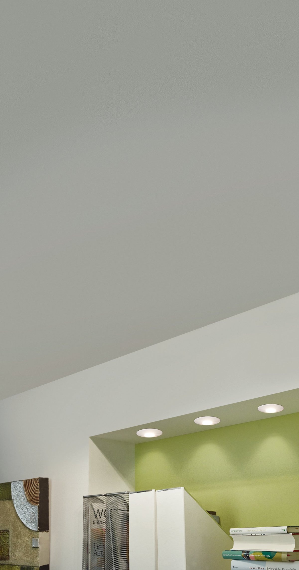 Trois spots encastrés dans un plafond blanc éclairant un mur vert menthe