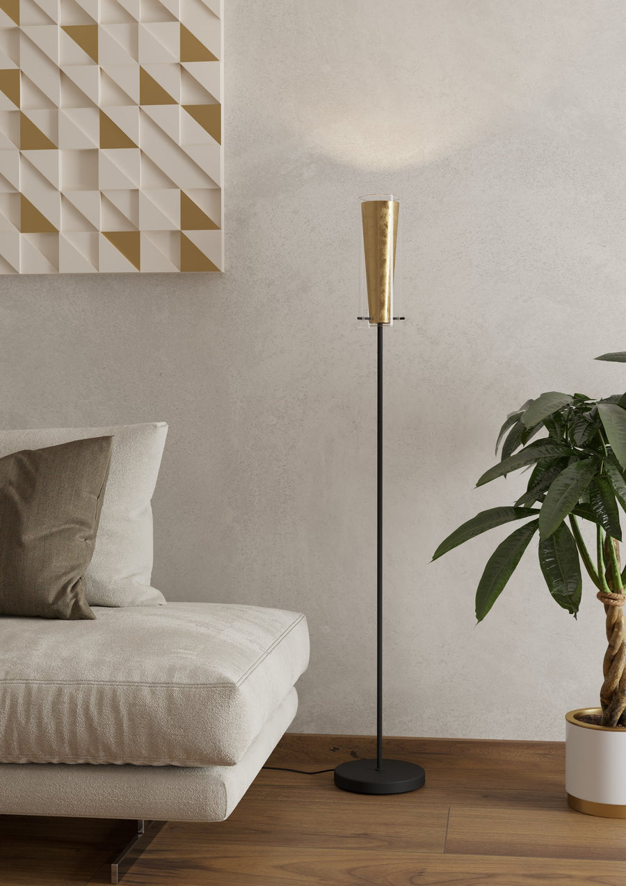 Lampadaire allumé près d'un canapé beige, mur texturé et grande plante verte