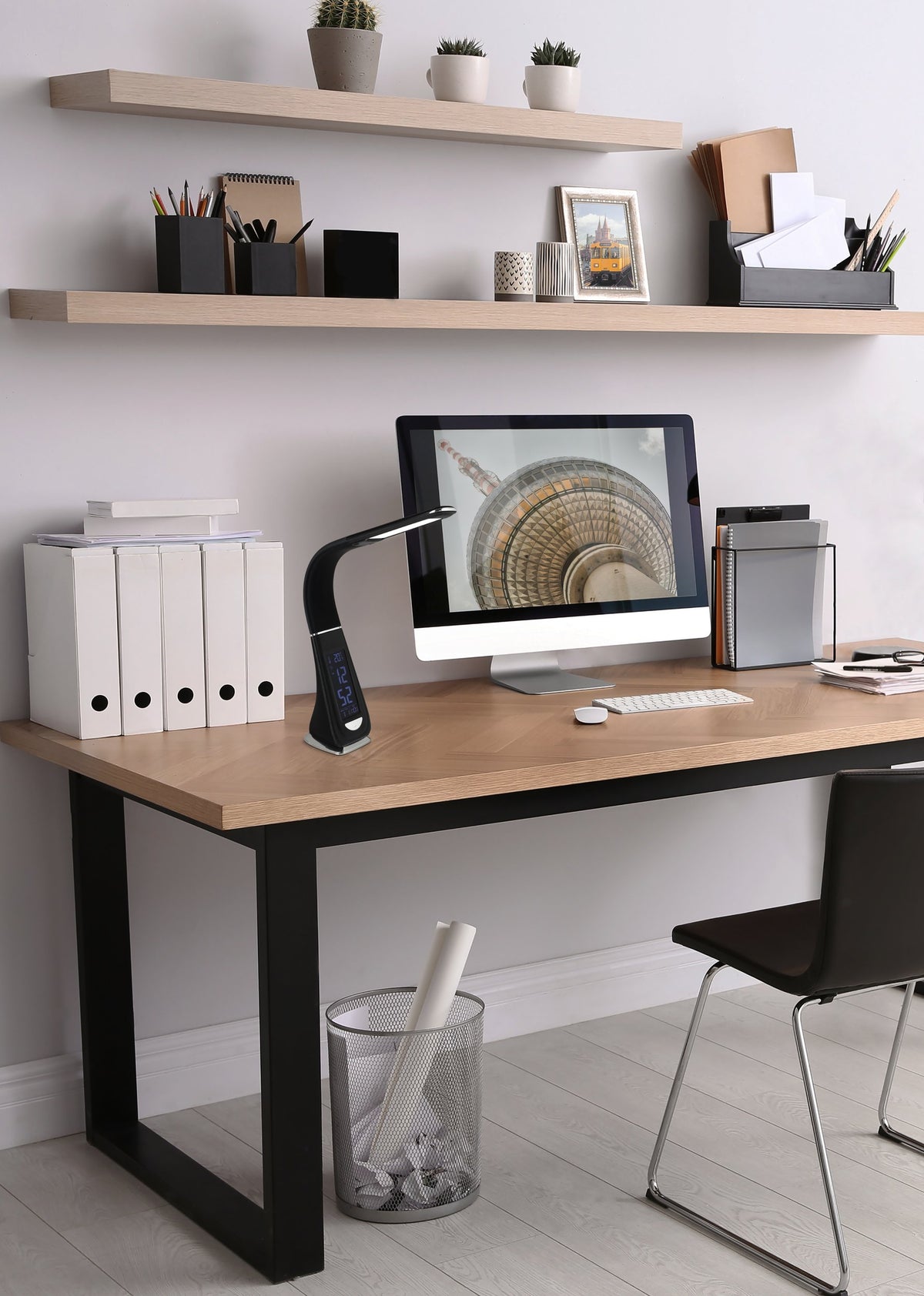 Mise en ambiance bureau : la lampe éclairée côtoie un écran, des classeurs et des étagères