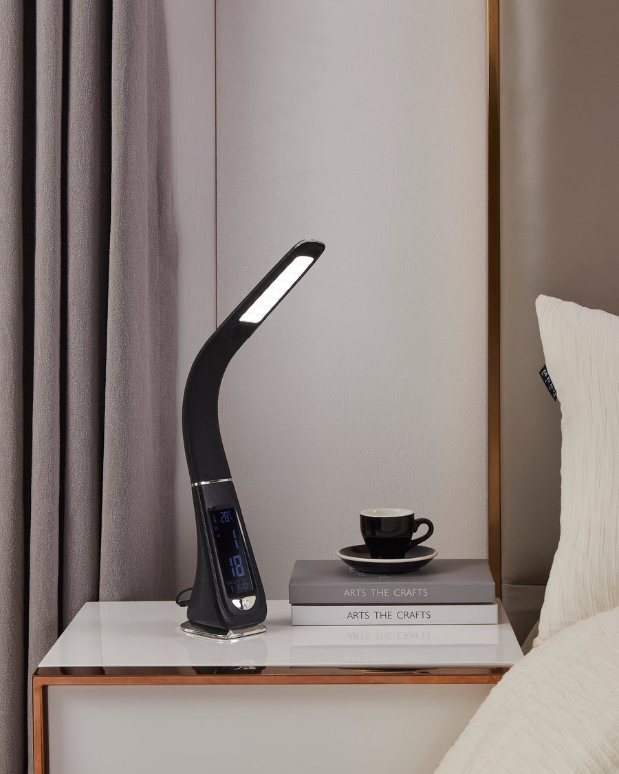 Ambiance chevet : lampe allumée près d'une tasse, de livres et d'un coussin blanc