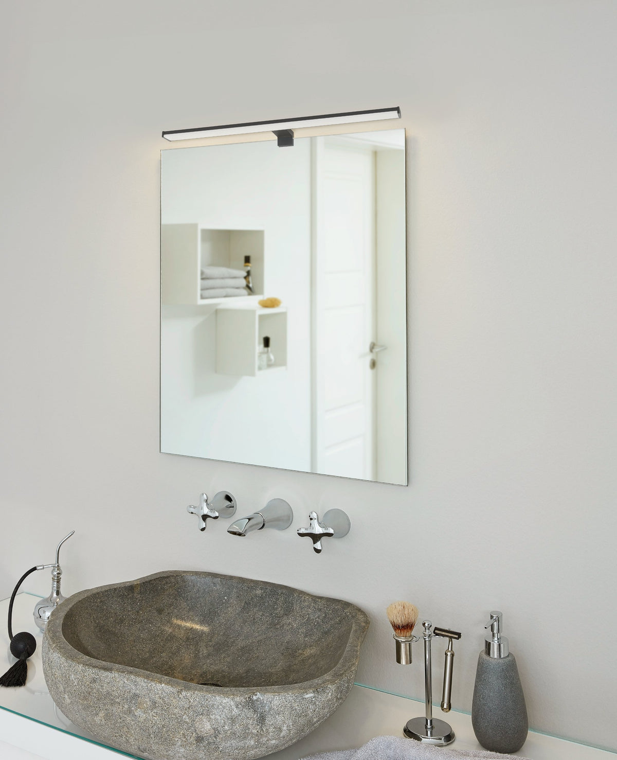 Mise en ambiance au-dessus d'un miroir de salle de bain avec vasque en pierre.