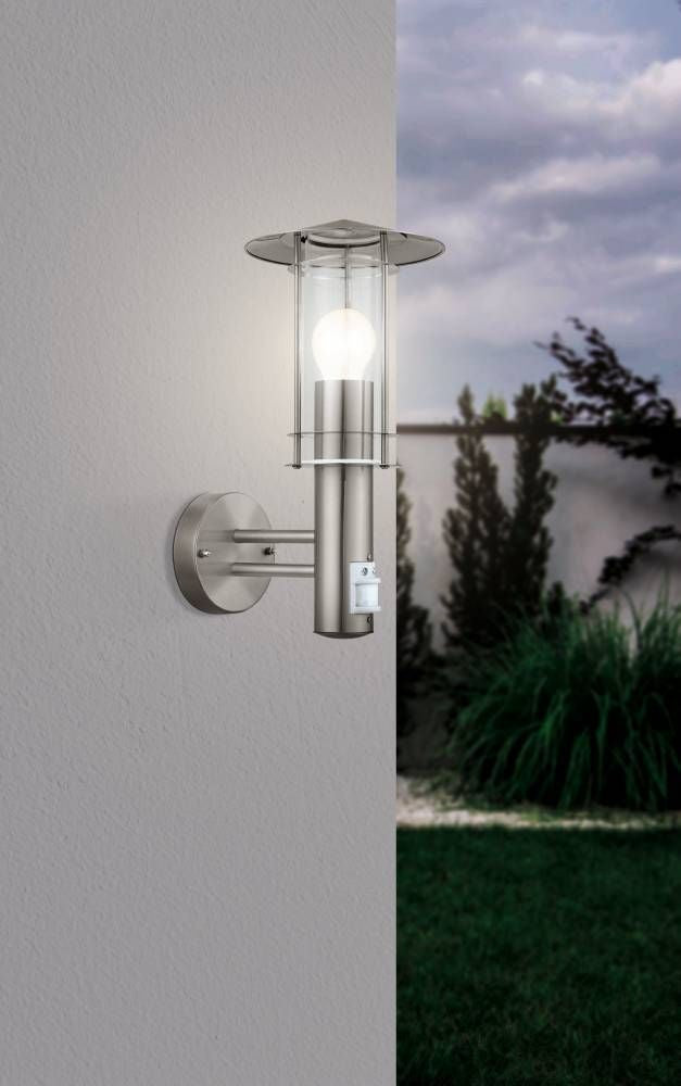 Mise en ambiance nocturne, applique allumée sur un mur extérieur près d'un jardin