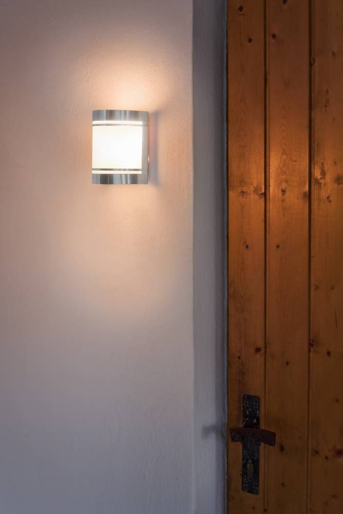 Mise en ambiance intérieure, applique allumée près d'une porte en bois