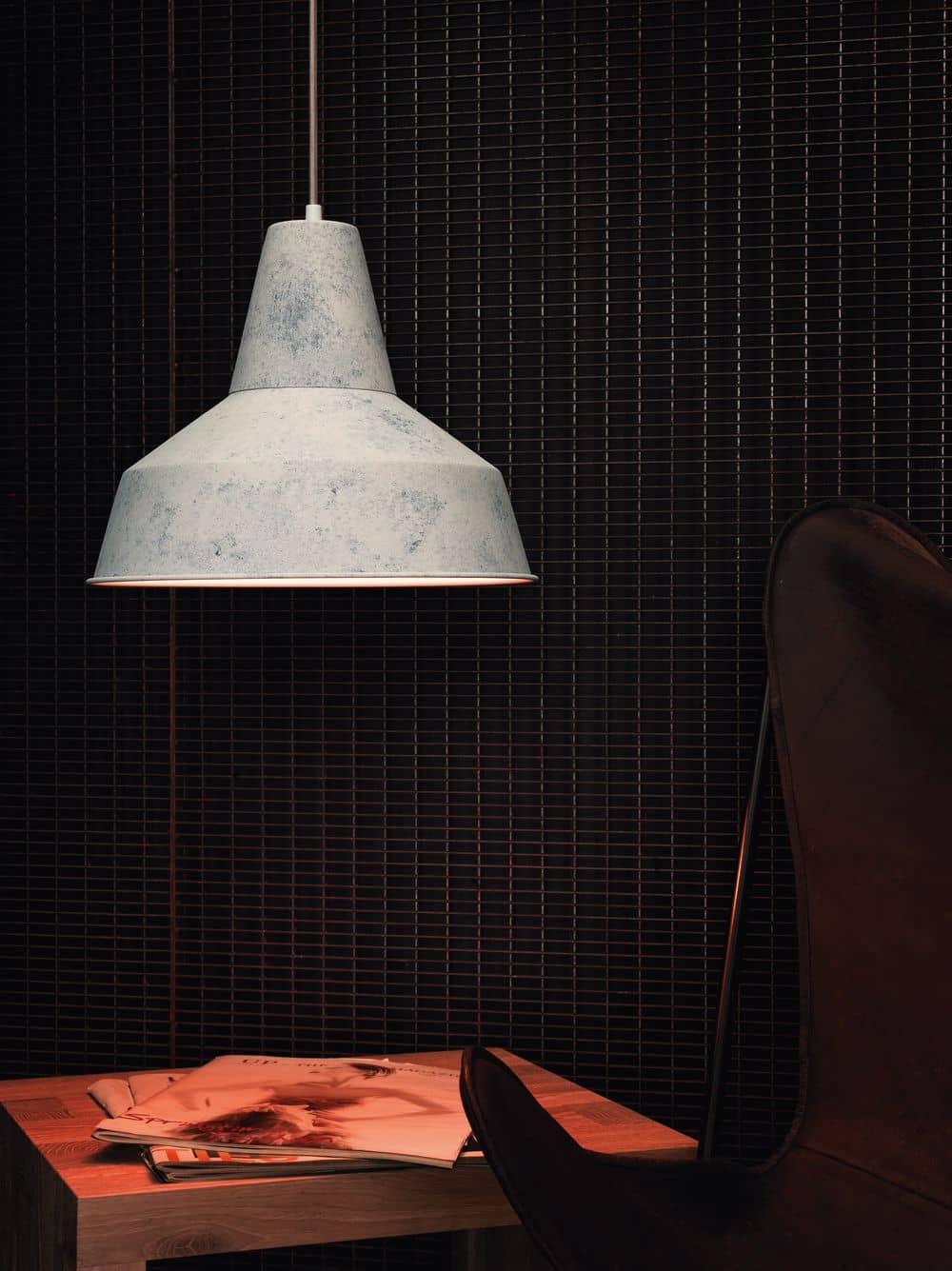 Mise en ambiance sombre, lampe suspendue au-dessus d'une table basse avec magazines