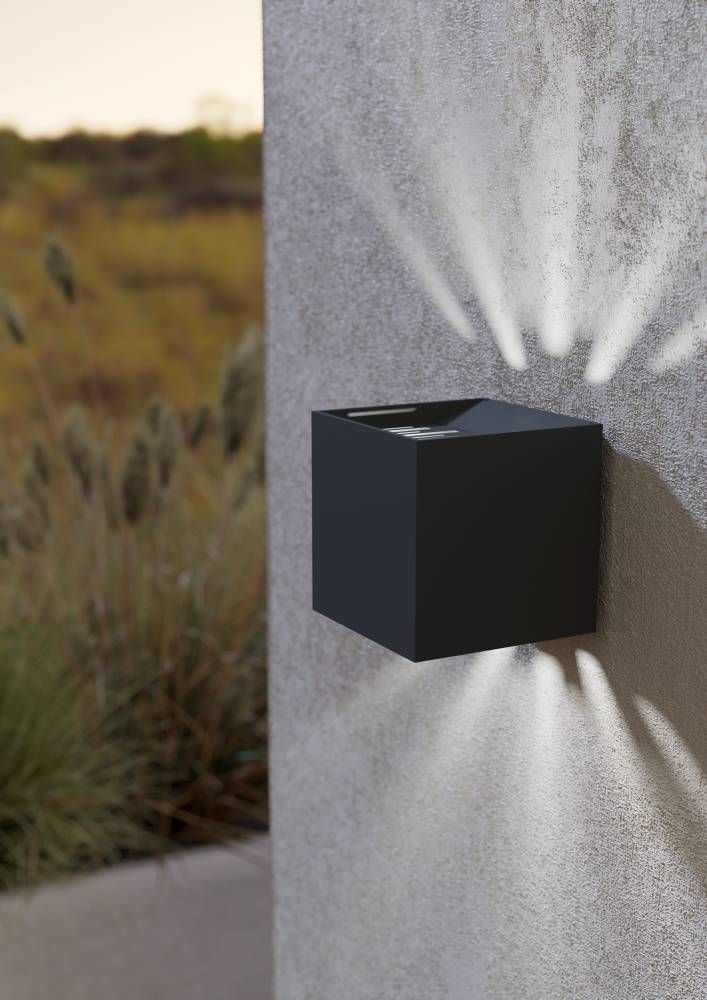 Applique extérieure cube anthracite fixée sur un mur texturé, éclairage en faisceaux haut et bas.